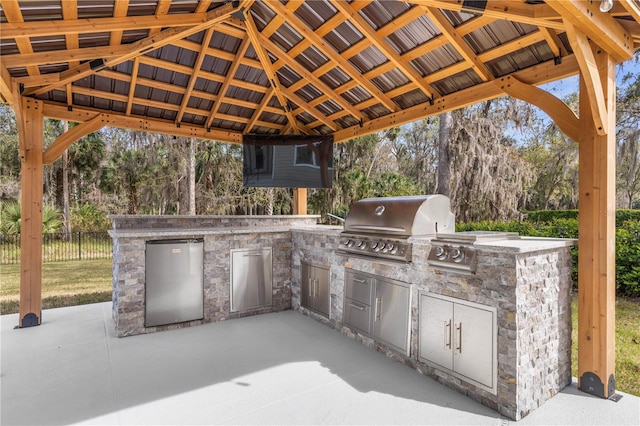 view of patio with exterior kitchen, fence, grilling area, and a gazebo