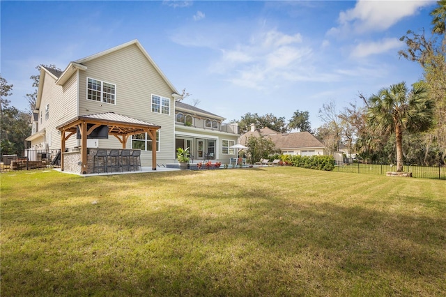 rear view of property featuring outdoor dry bar, a yard, fence, a gazebo, and a patio area