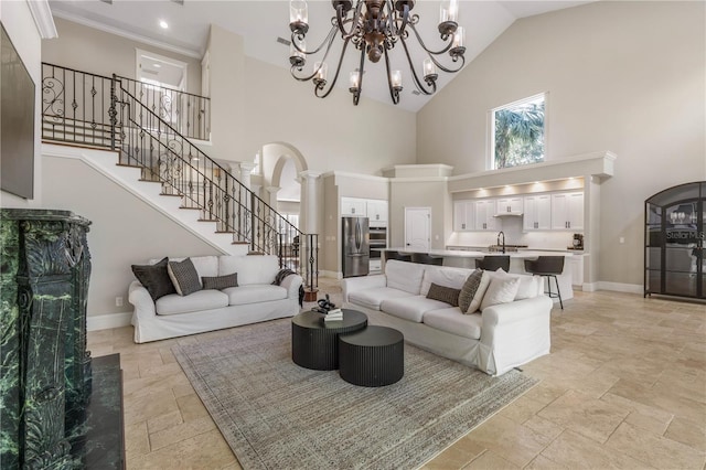 living area featuring arched walkways, decorative columns, baseboards, and stairs