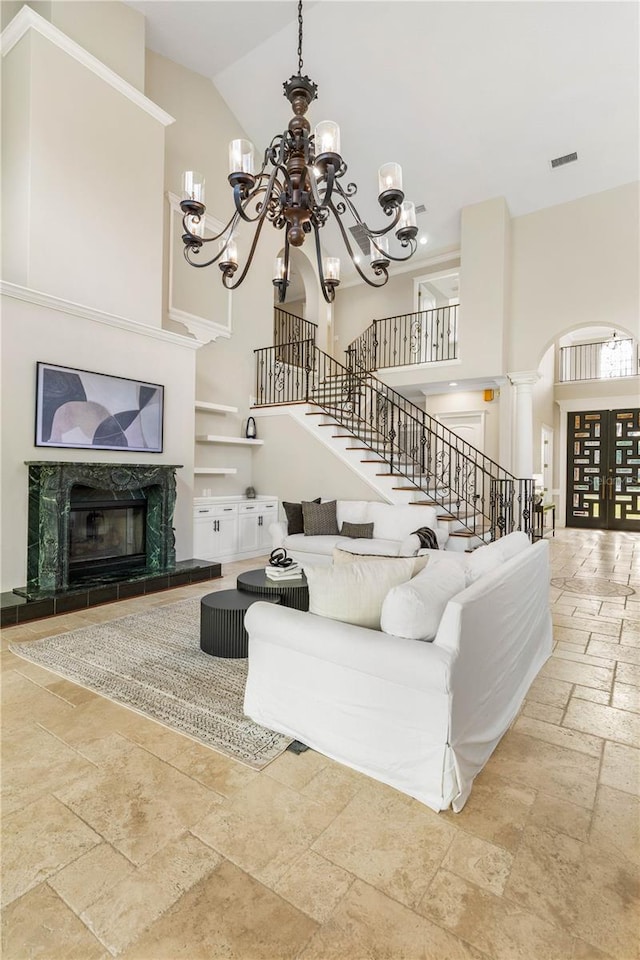 living area featuring stairs, a high ceiling, and a high end fireplace