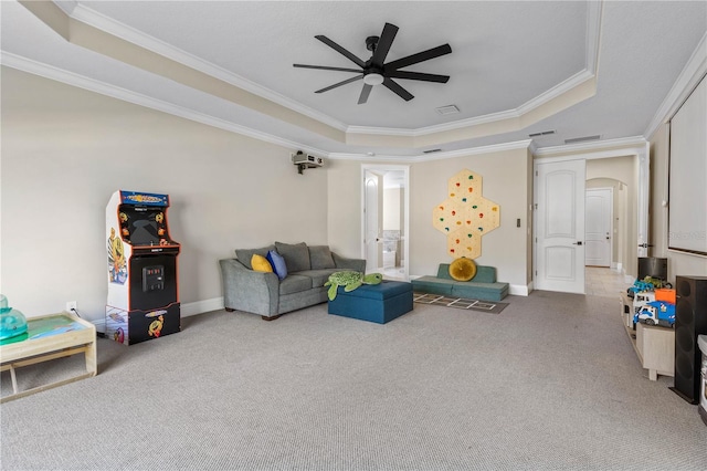 carpeted living area with ornamental molding, ceiling fan, a tray ceiling, and arched walkways