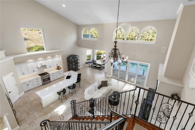 living room featuring visible vents, a chandelier, stone finish flooring, stairs, and high vaulted ceiling