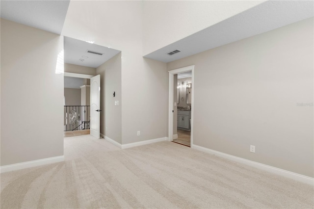 interior space featuring light carpet, baseboards, visible vents, and connected bathroom