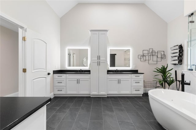 bathroom with a freestanding bath, high vaulted ceiling, two vanities, and a sink