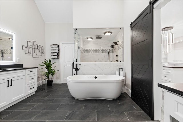 bathroom with a freestanding tub, baseboards, a tile shower, and vanity