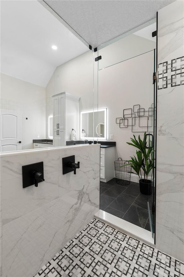 full bathroom with tile patterned flooring, vaulted ceiling, vanity, and a marble finish shower