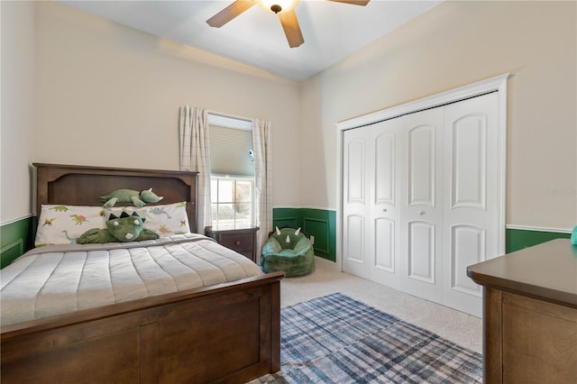 carpeted bedroom featuring a closet, wainscoting, and ceiling fan