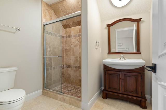 bathroom featuring vanity, a shower stall, toilet, and baseboards