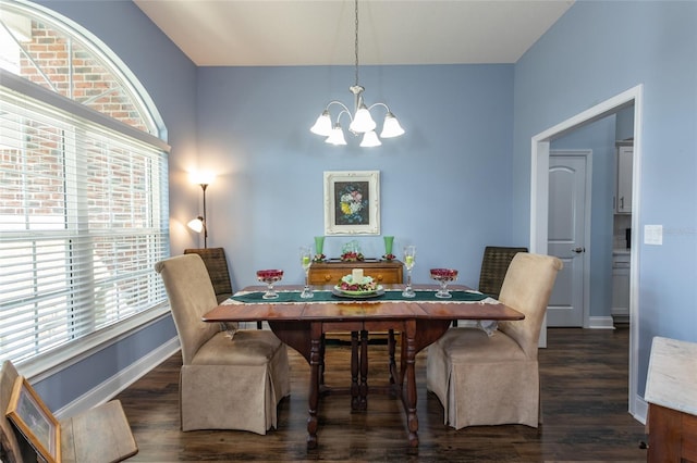 dining room featuring dark wood-style flooring, a notable chandelier, and baseboards