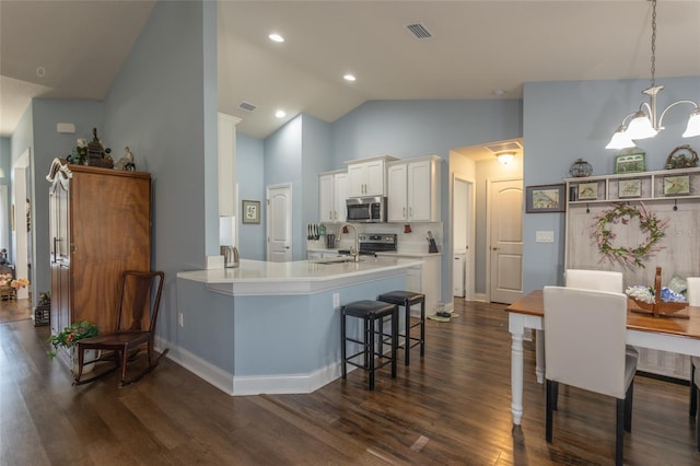 kitchen with dark wood-style flooring, stainless steel microwave, visible vents, white cabinetry, and a kitchen breakfast bar