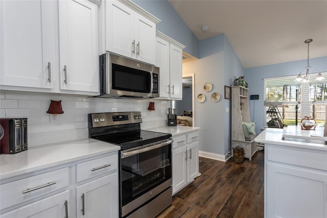 kitchen featuring vaulted ceiling, white cabinetry, stainless steel appliances, and a sink