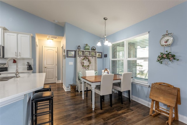 dining space with a chandelier, dark wood finished floors, vaulted ceiling, and baseboards