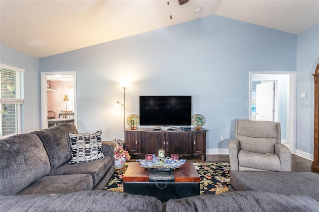 living area featuring baseboards, vaulted ceiling, and wood finished floors