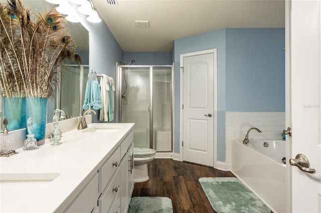 bathroom with double vanity, wood finished floors, a sink, and a shower stall