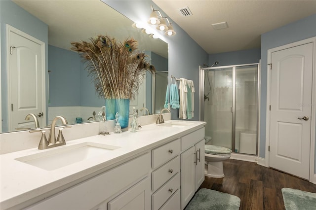 bathroom with a shower stall, visible vents, a sink, and wood finished floors