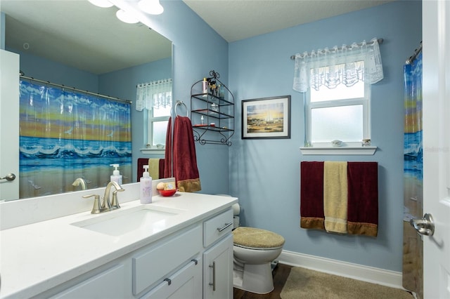 bathroom with toilet, vanity, a wealth of natural light, and baseboards