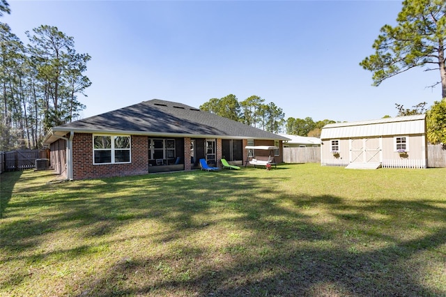 back of property featuring an outbuilding, brick siding, a yard, central AC, and a fenced backyard