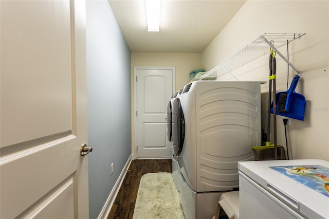 clothes washing area featuring laundry area, baseboards, dark wood-type flooring, a textured ceiling, and washer and dryer