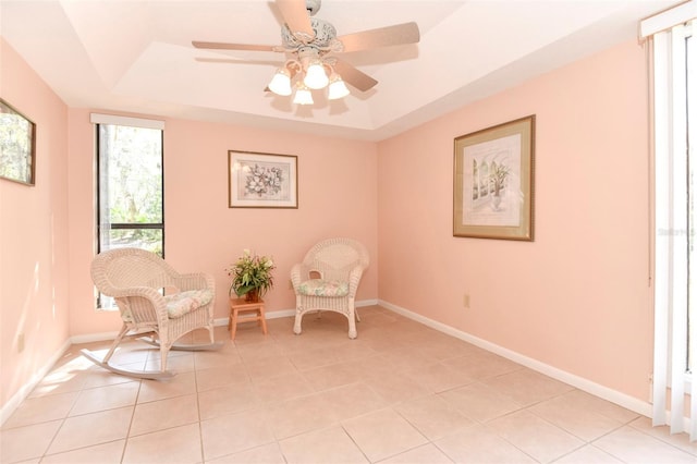 unfurnished room with light tile patterned floors, baseboards, a tray ceiling, and a ceiling fan