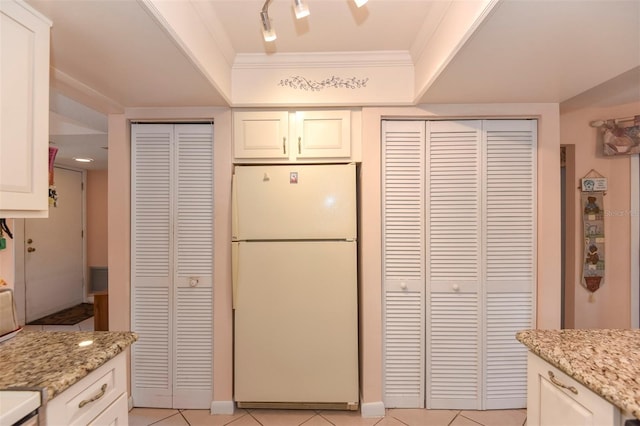 kitchen with light stone counters, freestanding refrigerator, crown molding, and light tile patterned floors