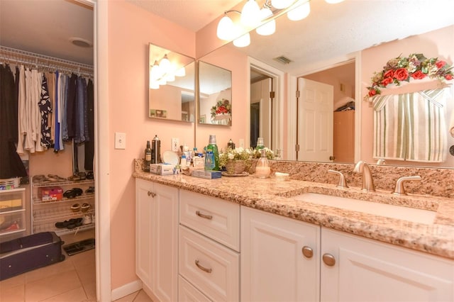 bathroom with vanity, visible vents, a walk in closet, and tile patterned floors