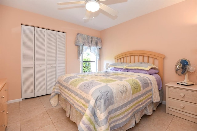 bedroom with a closet, light tile patterned flooring, a ceiling fan, and baseboards