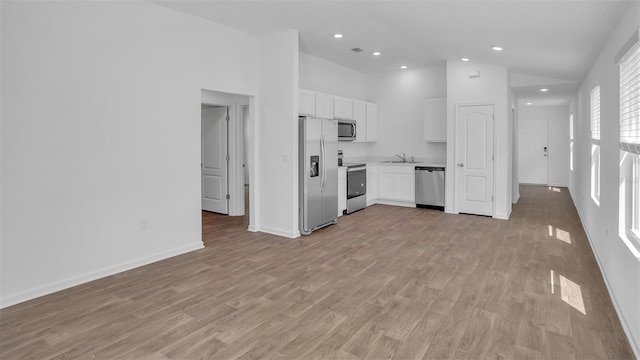 kitchen featuring light wood-style flooring, stainless steel appliances, a sink, white cabinets, and light countertops