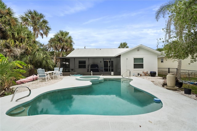 rear view of property featuring a patio, a sunroom, metal roof, fence, and a pool with connected hot tub