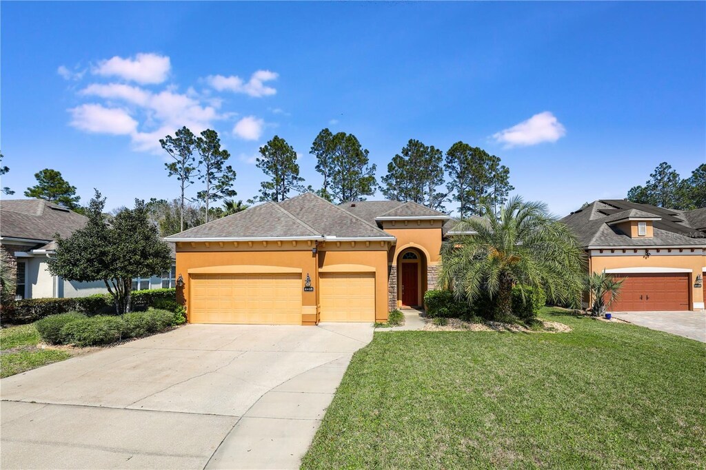 4468 Gray Hawk St, Orange Park, FL 32065 - view of front facade with stone siding, driveway, a garage, a front yard, and stucco siding
