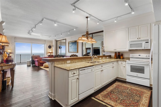 kitchen with a peninsula, white appliances, open floor plan, and a sink