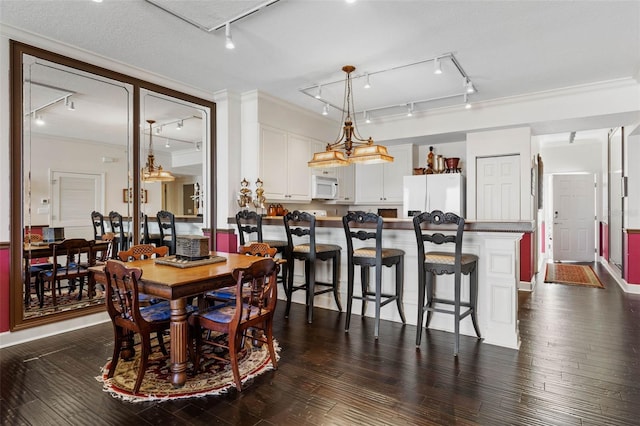 dining room with dark wood-style floors, track lighting, and crown molding