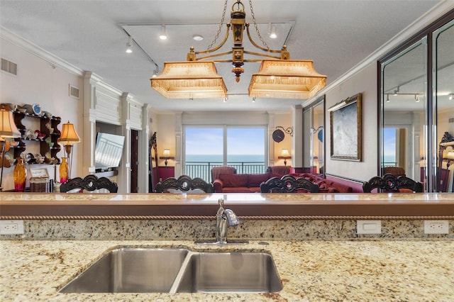 kitchen with crown molding, visible vents, light stone counters, and a sink