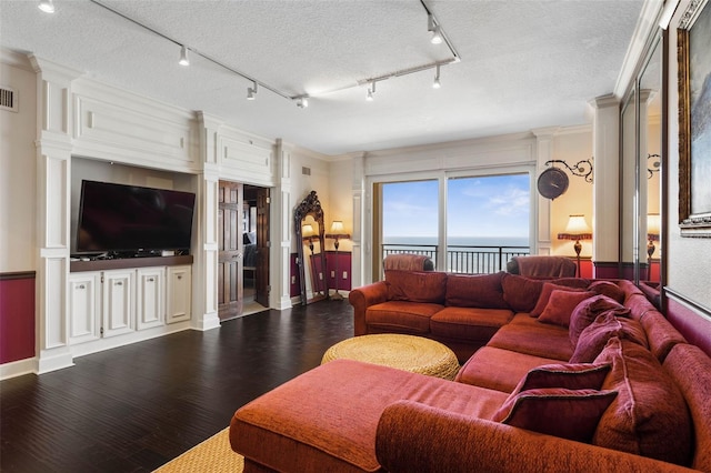 living room with a textured ceiling, dark wood-type flooring, ornamental molding, and visible vents