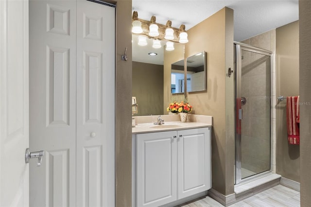 bathroom with a closet, baseboards, a shower stall, and vanity