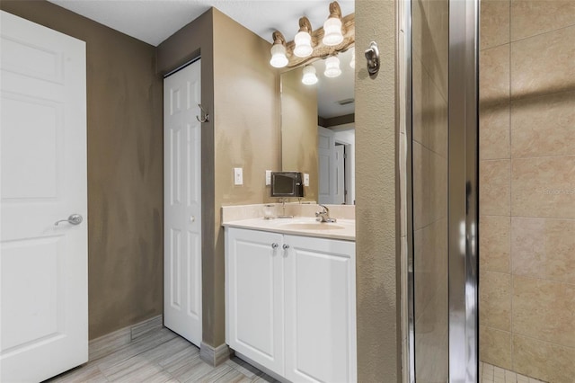 bathroom with a tile shower and vanity