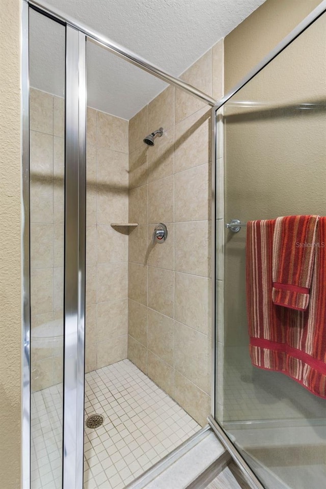 bathroom with a stall shower and a textured ceiling