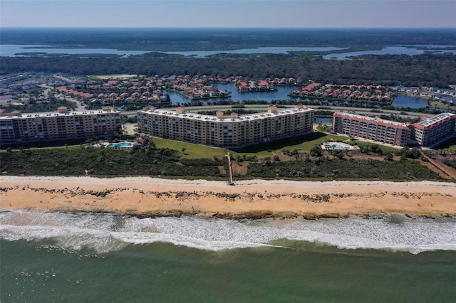 drone / aerial view featuring a water view, a view of the beach, and a city view