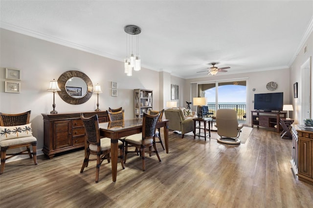 dining space with crown molding, baseboards, ceiling fan, and wood finished floors