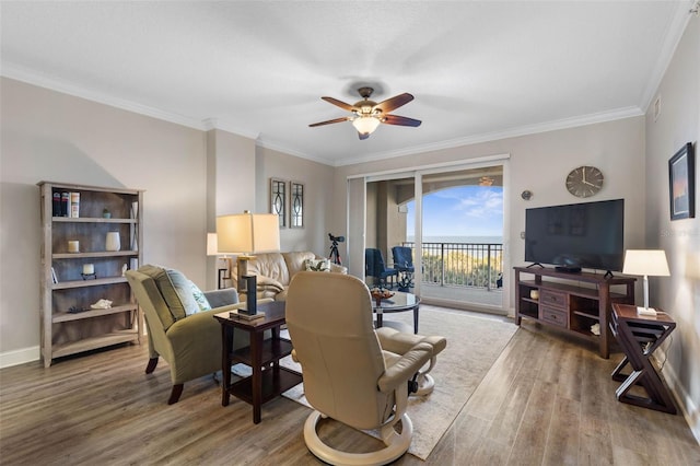 living room featuring ceiling fan, baseboards, wood finished floors, and crown molding