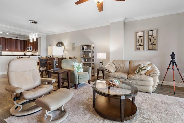 living area with light wood-style floors, crown molding, baseboards, and a ceiling fan