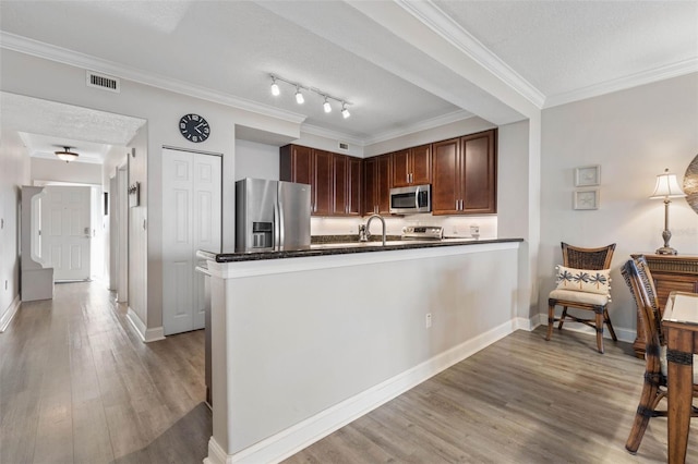 kitchen with dark countertops, a peninsula, visible vents, and stainless steel appliances