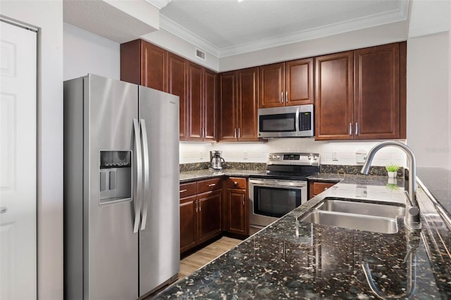 kitchen with stainless steel appliances, dark stone countertops, a sink, and visible vents