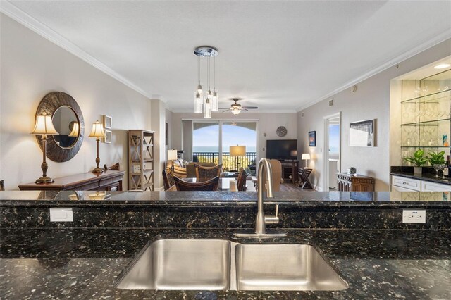 kitchen featuring open floor plan, ornamental molding, and a sink