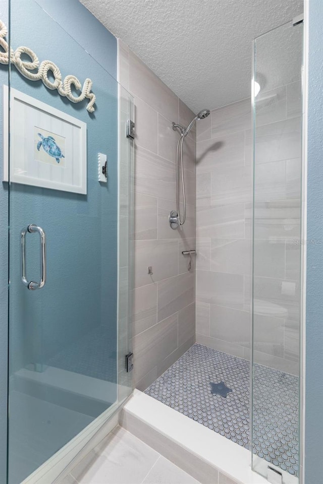 bathroom with a shower stall and a textured ceiling