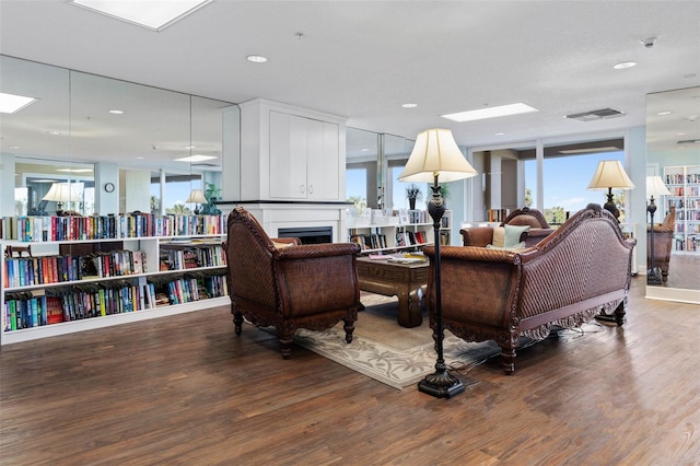 living room featuring a fireplace, visible vents, and wood finished floors