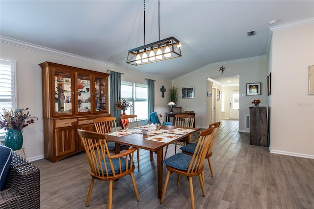 dining area with light wood finished floors, baseboards, arched walkways, ornamental molding, and vaulted ceiling