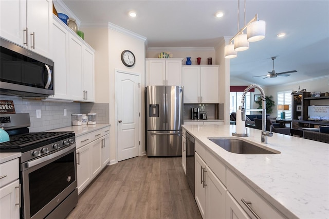 kitchen with stainless steel appliances, white cabinets, crown molding, and a ceiling fan