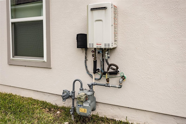 exterior details with gas meter, tankless water heater, and stucco siding