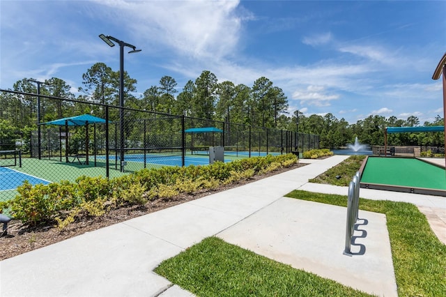 view of home's community featuring a tennis court and fence