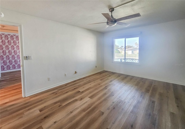 empty room featuring a textured ceiling, baseboards, and wood finished floors